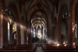 Betender Mann im Hauptchor der Stiftskirche Baden-Baden mit gotischen Gewölben und farbigem Lichtspiel vor der Renovierung