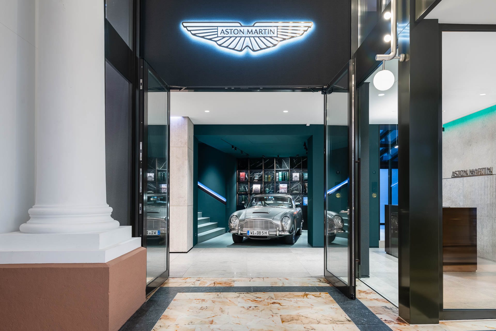 Eingang des Aston Martin Showrooms in Baden-Baden mit klassischem DB5 im Hintergrund