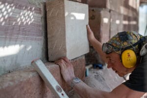 Steinmetz setzt Sandsteinblock in historische Fassade ein